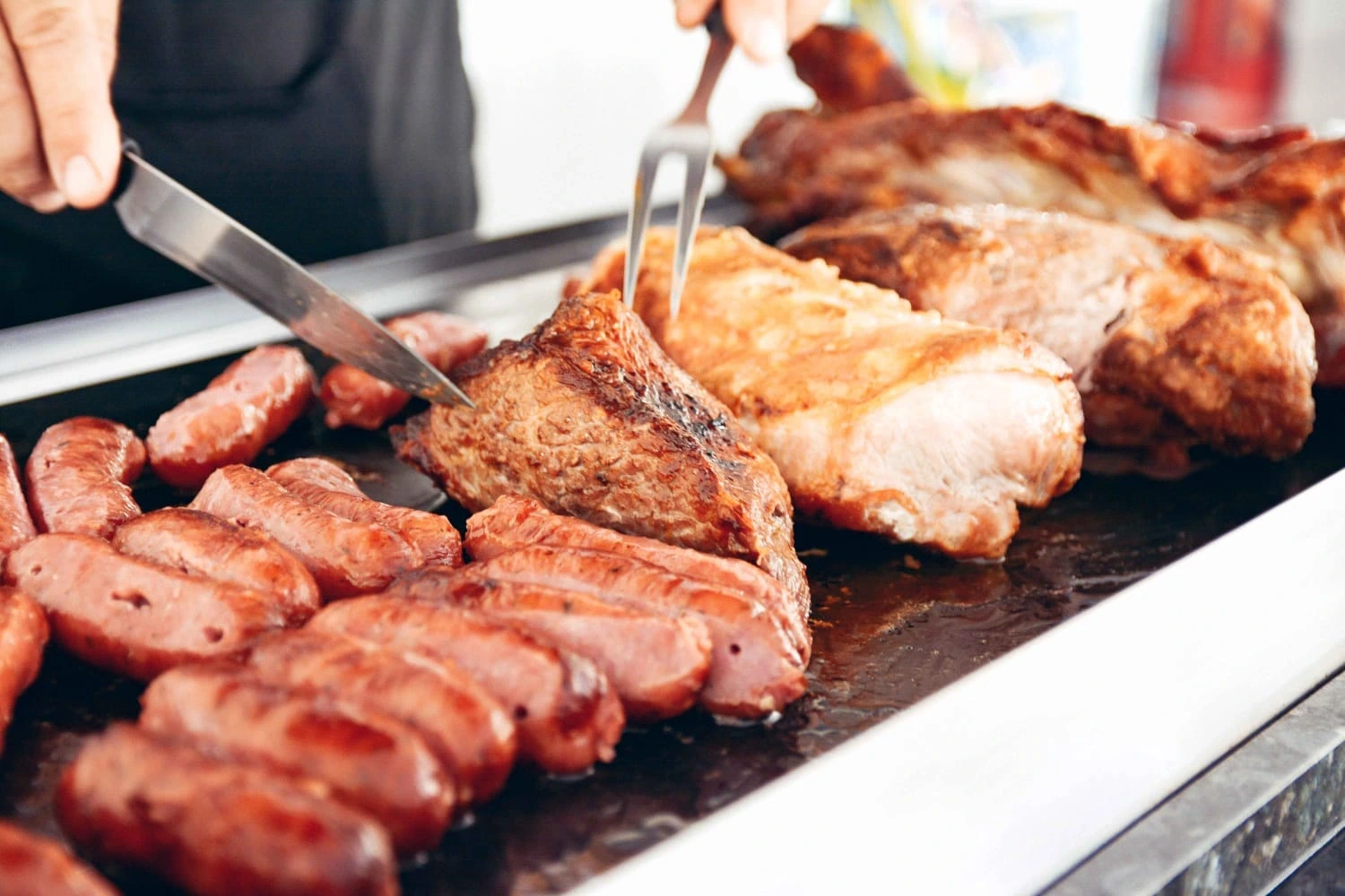 Carnes sendo cortadas na churrasqueira.